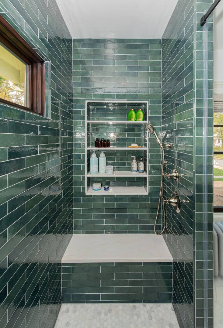 Green tiled shower with built-in bench and niche shelving in a Caldwell, NJ custom home by G&L and Sons Renovations