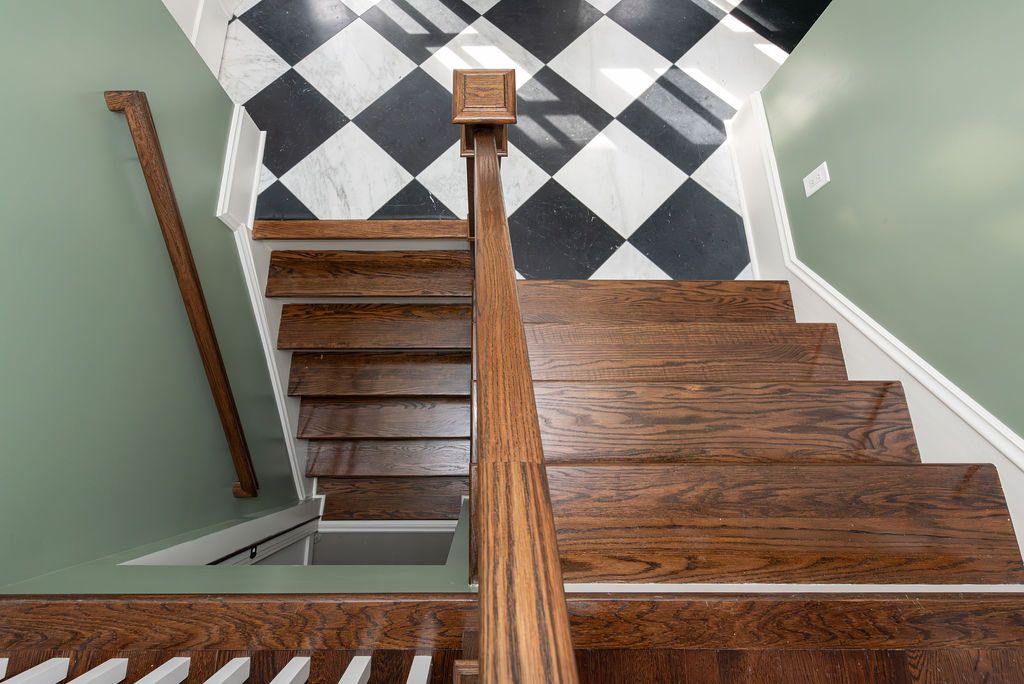 Staircase renovation with dark wood treads and checkerboard tile landing in West Caldwell, NJ by G&L and Sons Renovations